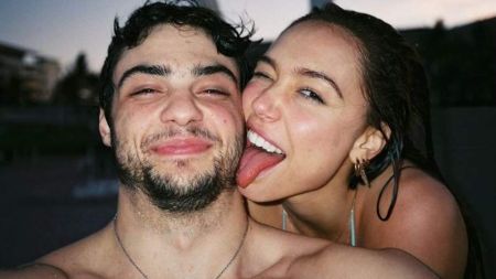 Noah Centineo and Alexis Ren pose at the pool.
